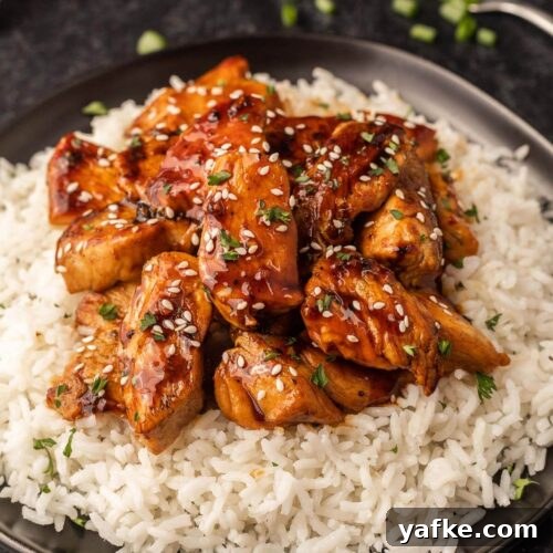 Low-Carb Chicken Recipes for Your Blackstone Griddle 12 Chicken with sesame seeds and rice on a black plate.