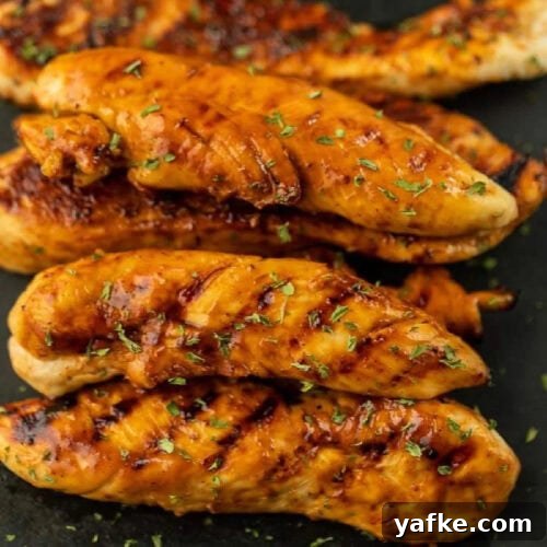 Low-Carb Chicken Recipes for Your Blackstone Griddle 16 Juicy grilled chicken tenders with herbs on black plate.