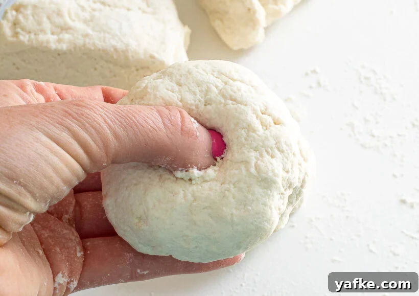A finger pressing a hole into a ball of dough.