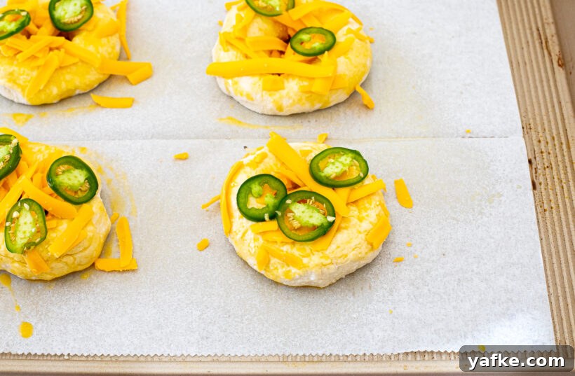 Bagels topped with shredded cheese and jalapeno slices.