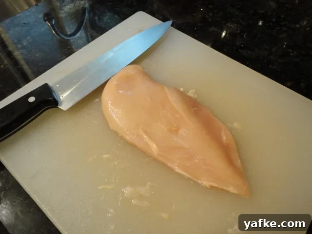 Place the chicken breast on the cutting board with the knife parallel to the cutting board